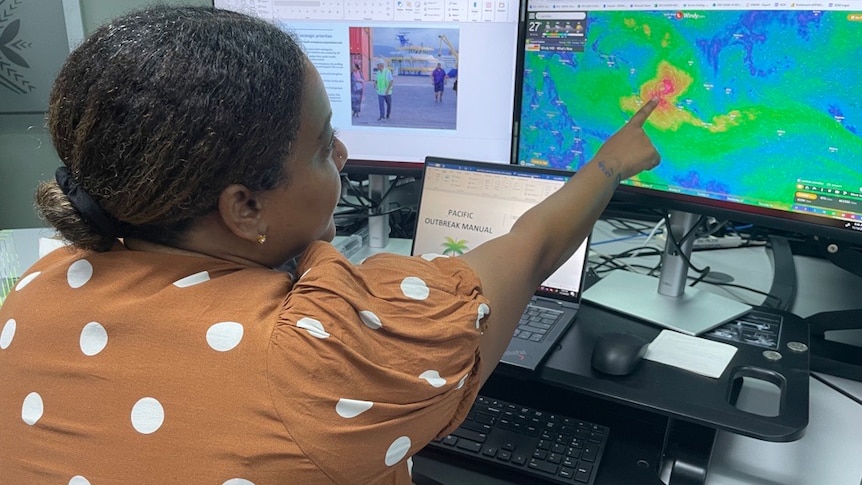 A Fijian woman points to display screens of a developing cyclone