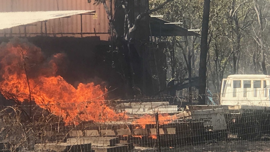 Fire burns near a truck on a property in the bush.