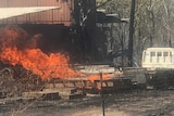 Fire burns near a truck on a property in the bush.