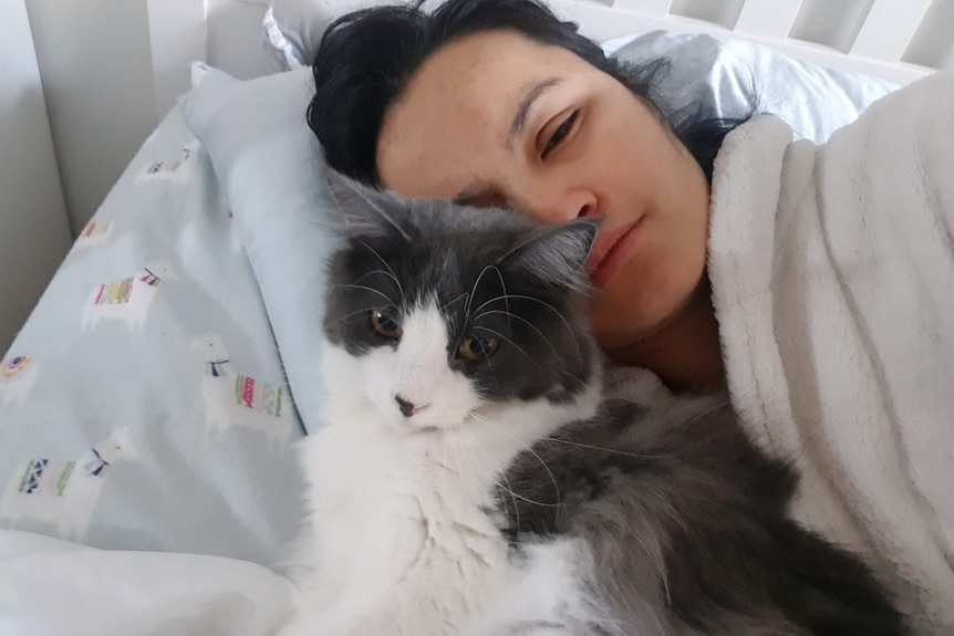 Judy in bed looking groggy with her cat