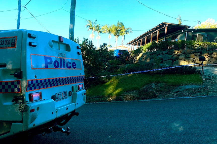 A police car parked outside a home with a police tape cordon.