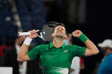 Novak Djokovic closes his eyes and pumps his fists in triumph after winning a tennis match in Dubai.