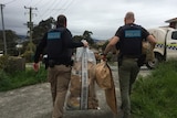 Two police officers walking away holding two large plastic bags 