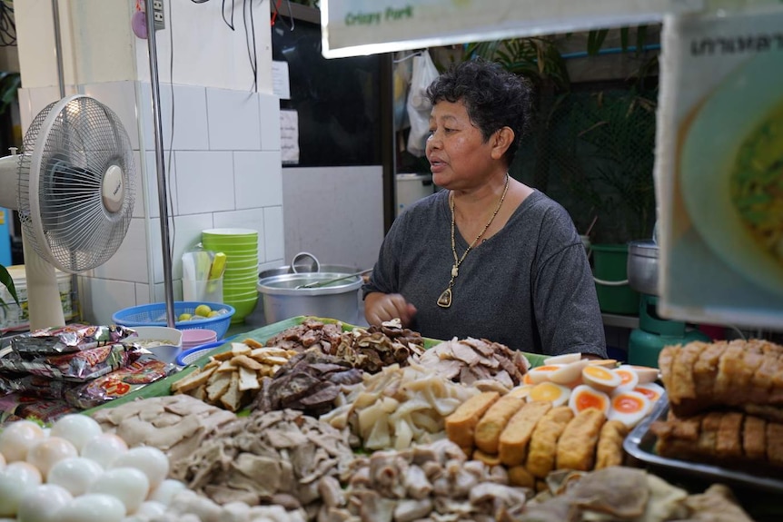 Woman sells food in a street food market stall