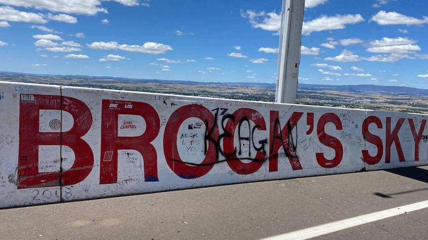 The concrete wall of a race track with big red lettering that says 'Brock's' with small 'Keagan' spray painted over the top.