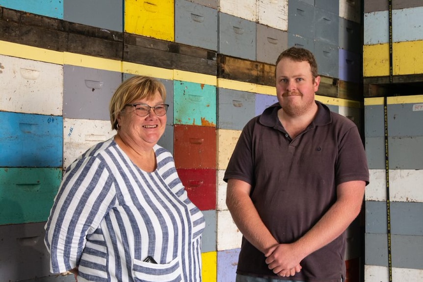 A woman and man standing in front of empty bee hive boxes