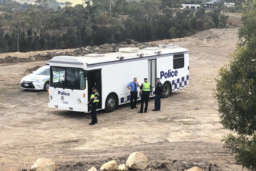 Police stand outside a police vehicle.