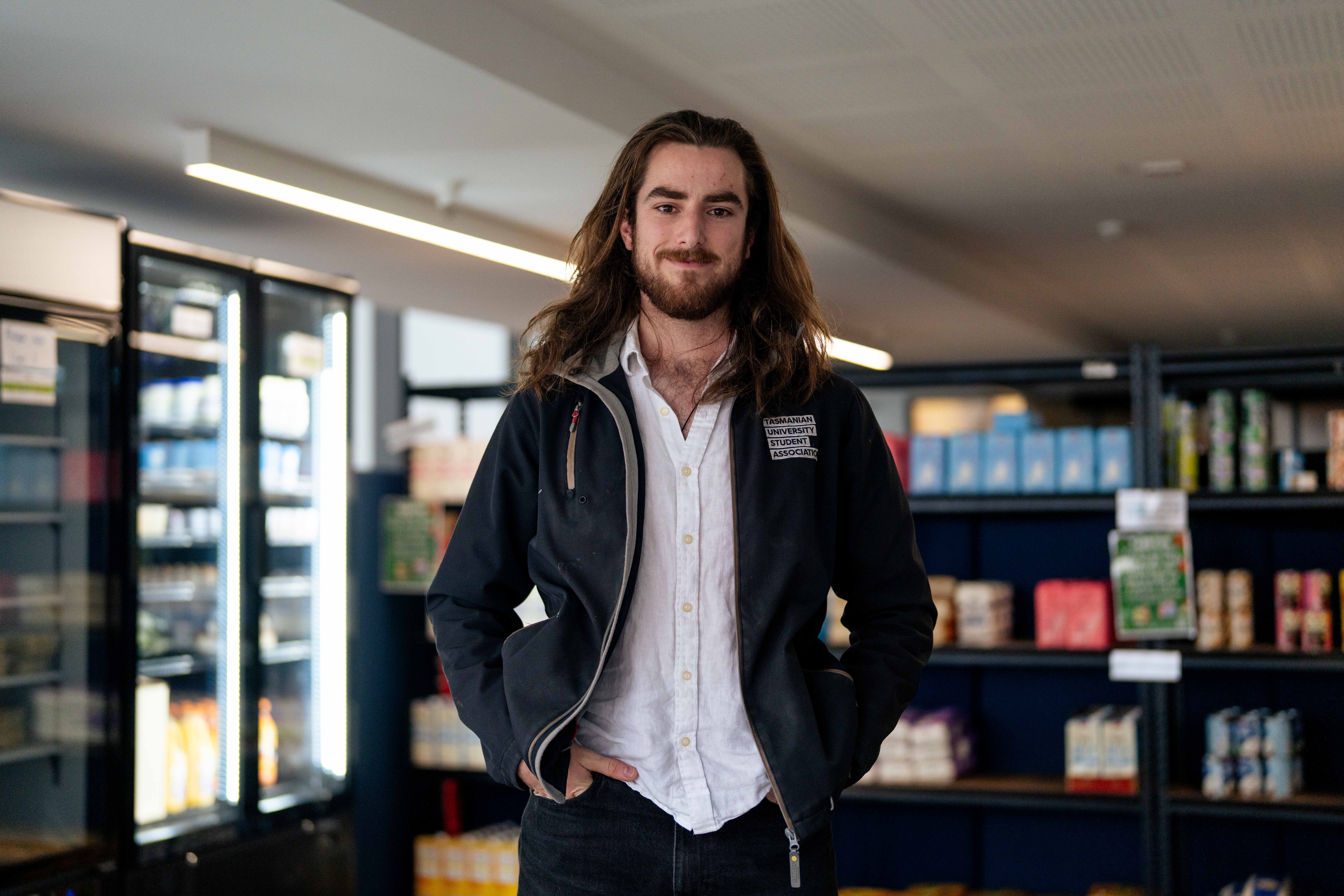 A man smiles for a photo in a mini grocery store