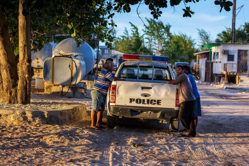 Four men lean on a police ute on Enetewak Atoll, Marshall Islands, October 2017.