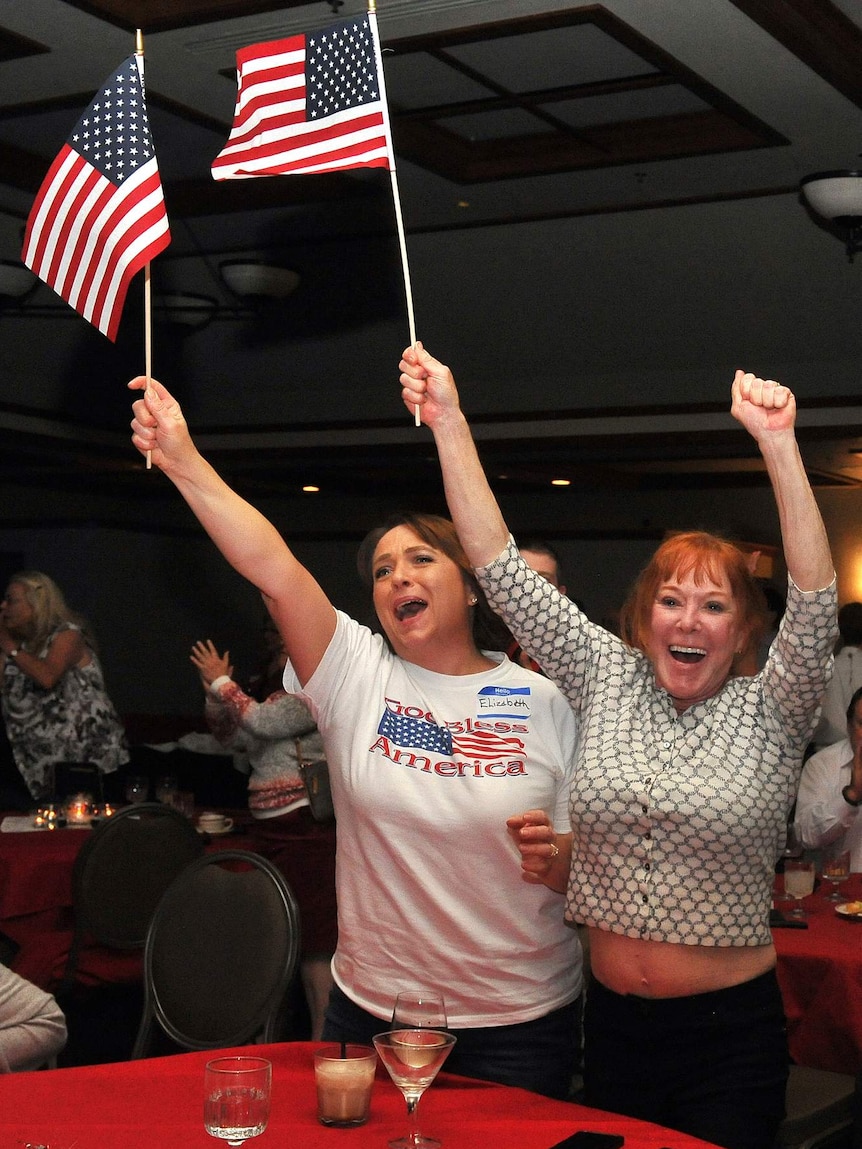 Two women wave American flags jubilantly.