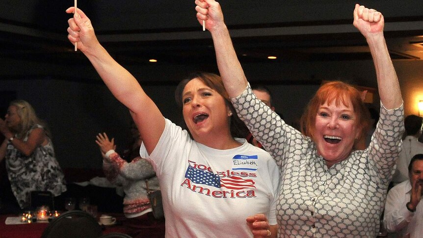 Two women wave American flags jubilantly.