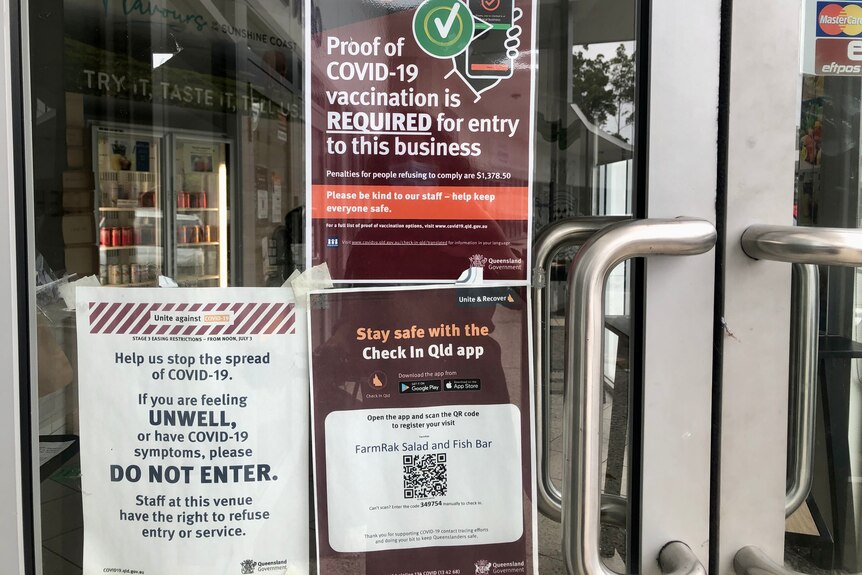 Signs including check-in Queensland app and need for proof of vaccination certificate.