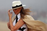 Melania Trump holds her hat down over her head while on a tour of the pyramids in Cairo, Egypt