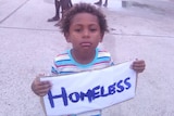 A boy holds a sign saying 'homeless' at a protest on Yam Island in the Torres Strait.