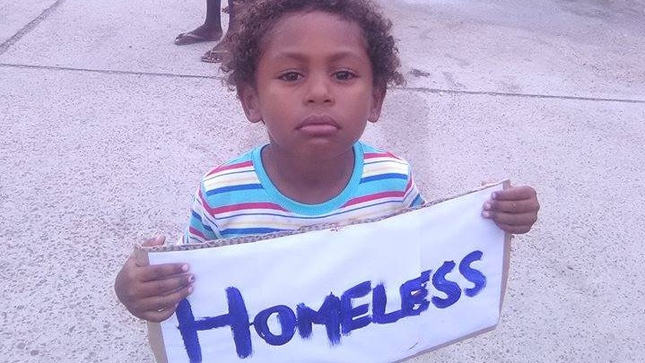 A boy holds a sign saying 'homeless' at a protest on Yam Island in the Torres Strait.