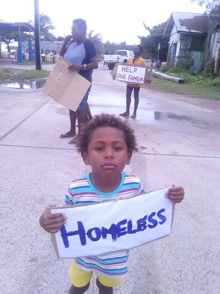 A boy holds a sign saying 'homeless' at a protest on Yam Island in the Torres Strait.