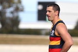 Adelaide Crows player Taylor Walker stands alone on an AFL field with his hands on his hips.