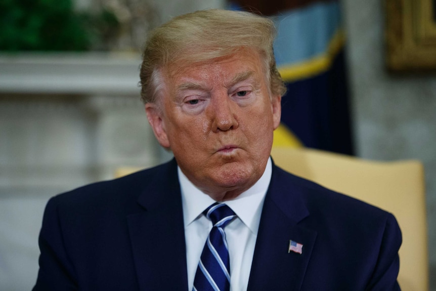 President Donald Trump listens to a question during a meeting in the Oval Office.