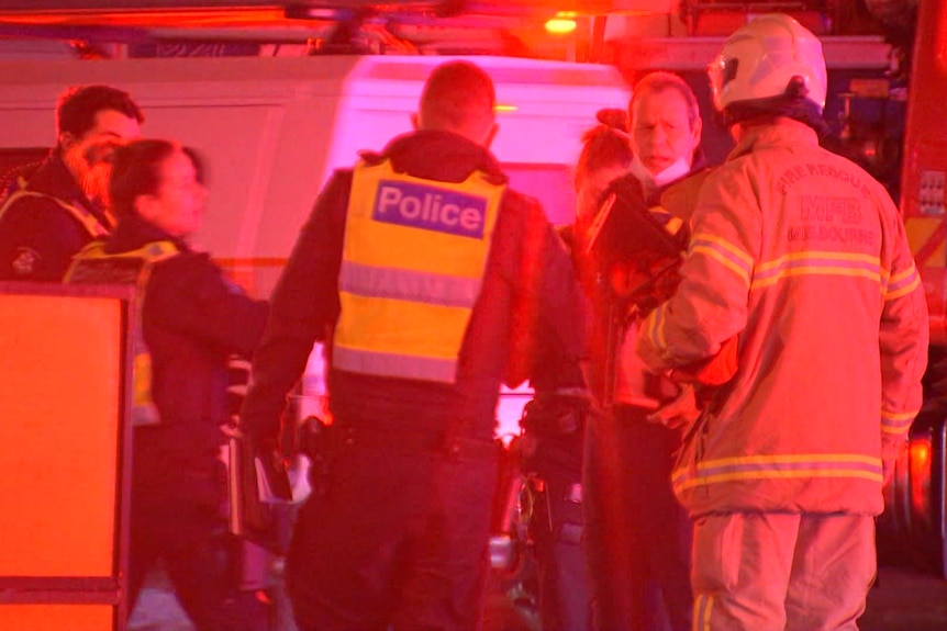 A group of police officers and firefighters talk together at the scene of the fire.