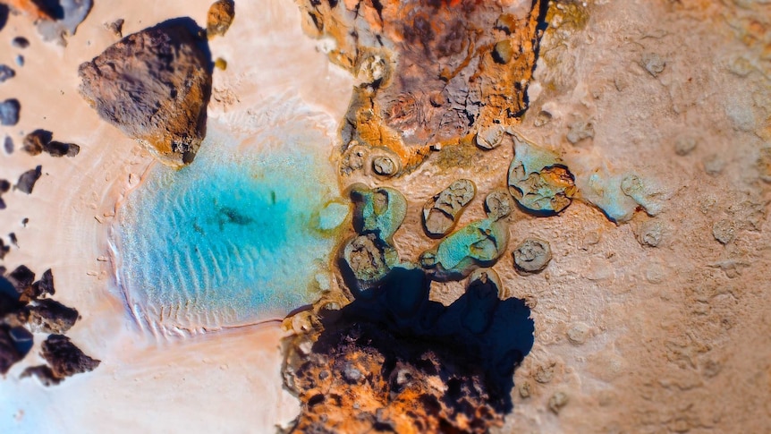 A top-down view of sand and rocks in a rock pool.