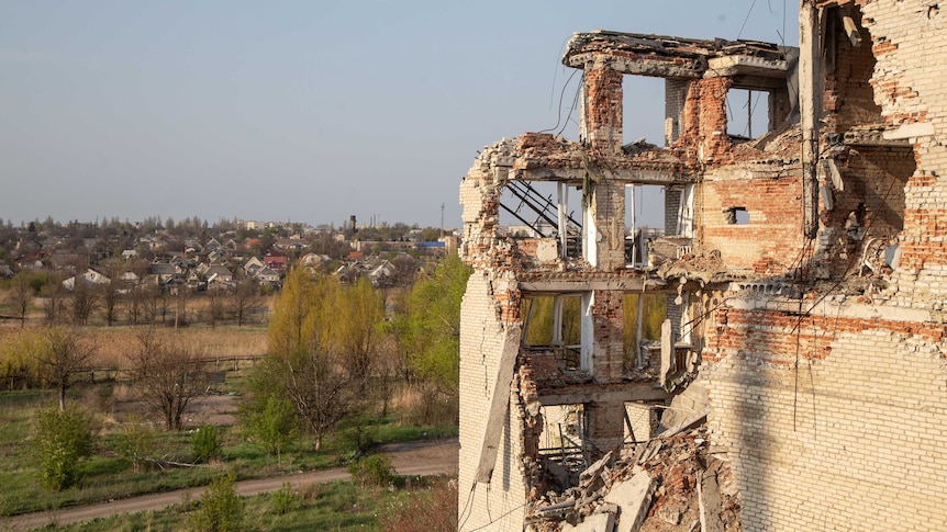 A crumbling building overlooks a town.