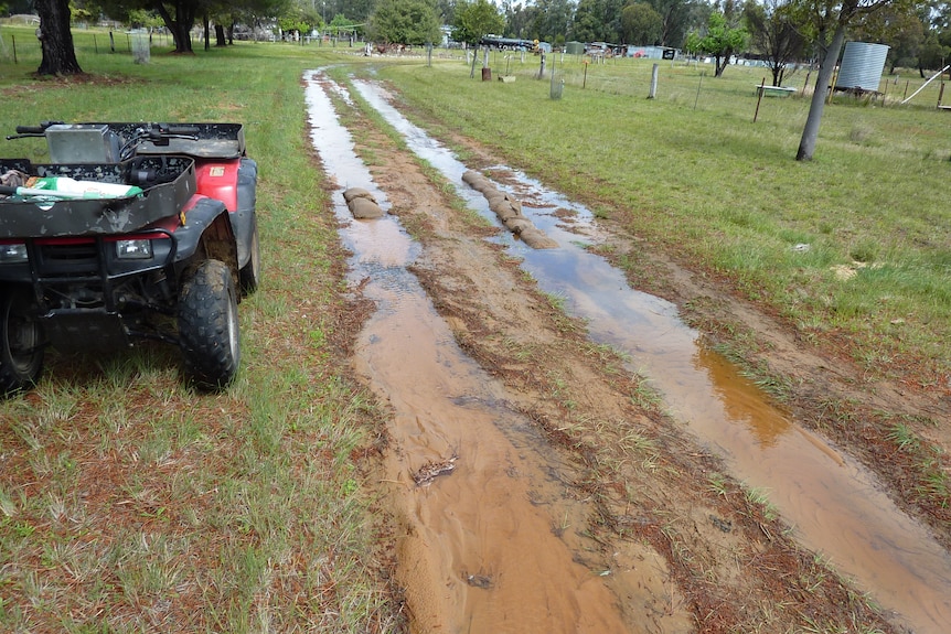 Dirt driveway filled with water and sandbags placed in some spots