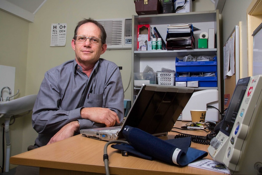 Dr David Outridge sits at a desk in his surgery.