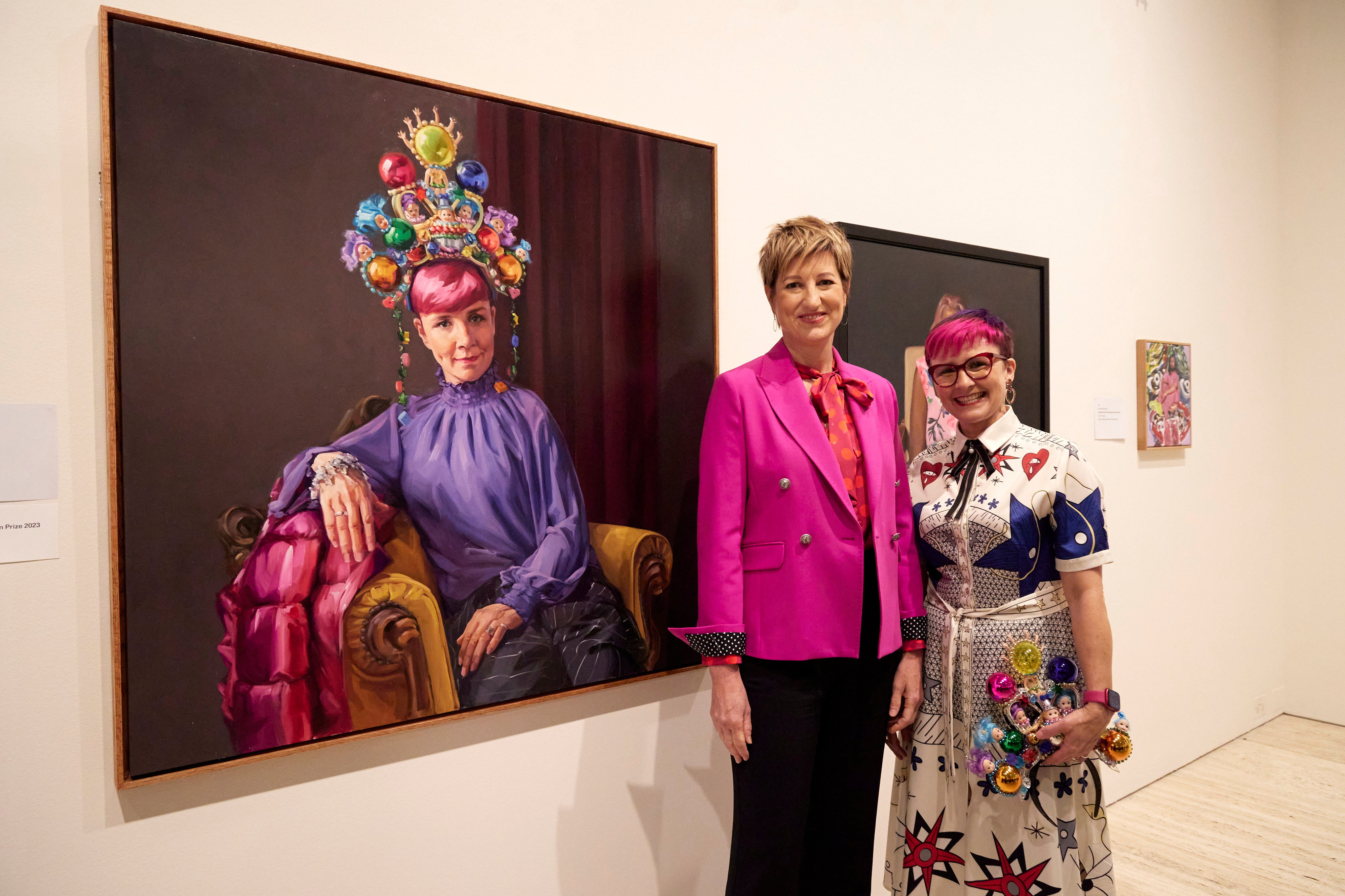 Artist Andrea Huelin and comedian Cal Wilson stand in front of a vibrant portrait of Cal.