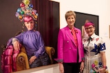 Artist Andrea Huelin and comedian Cal Wilson stand in front of a vibrant portrait of Cal.