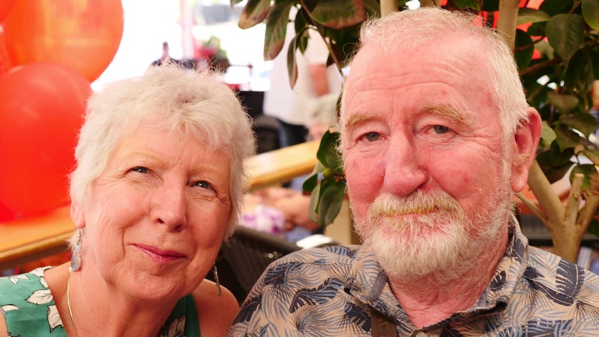 a woman and man close in looking at a camera in a cafe setting