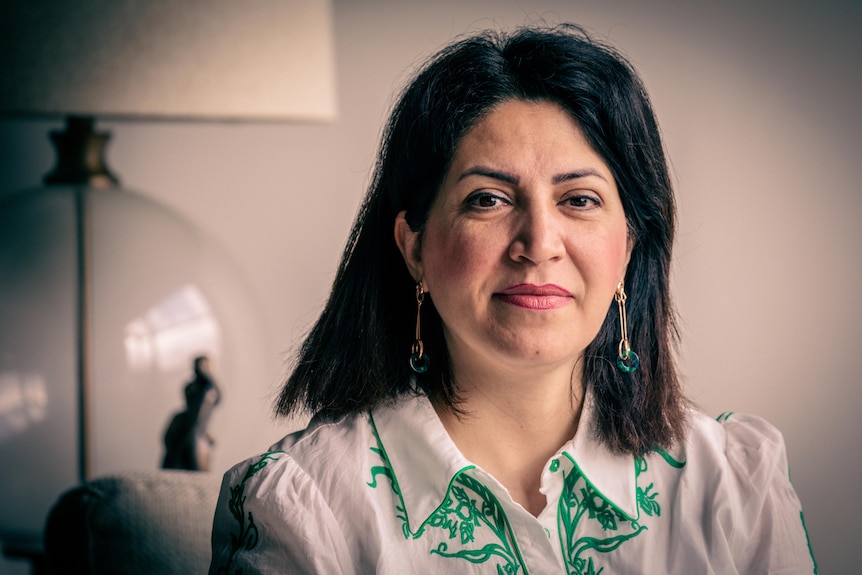 A woman with shoulder-length dark hair looks directly into the camera