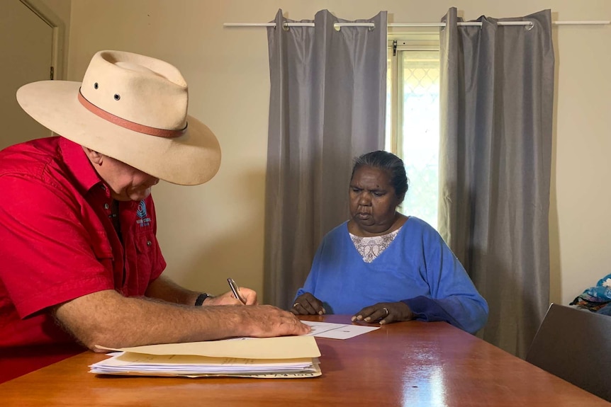 Leah Dolby reviews paperwork with Alan Gray at a table.