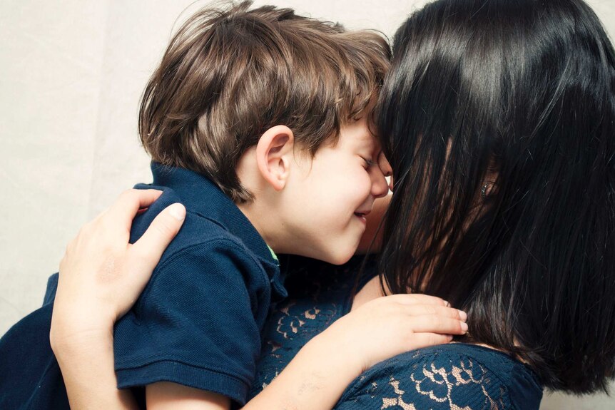 A boy cuddles his mother