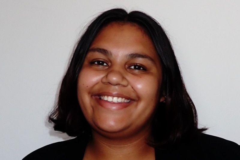 A young woman smiles brightly at the camera.