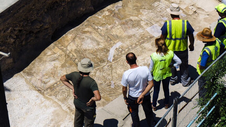 Archaeologists look at a rare Roman mosaic that has been uncovered in Cyprus