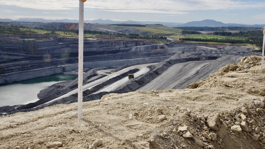 A coal pit with green hills in the background.