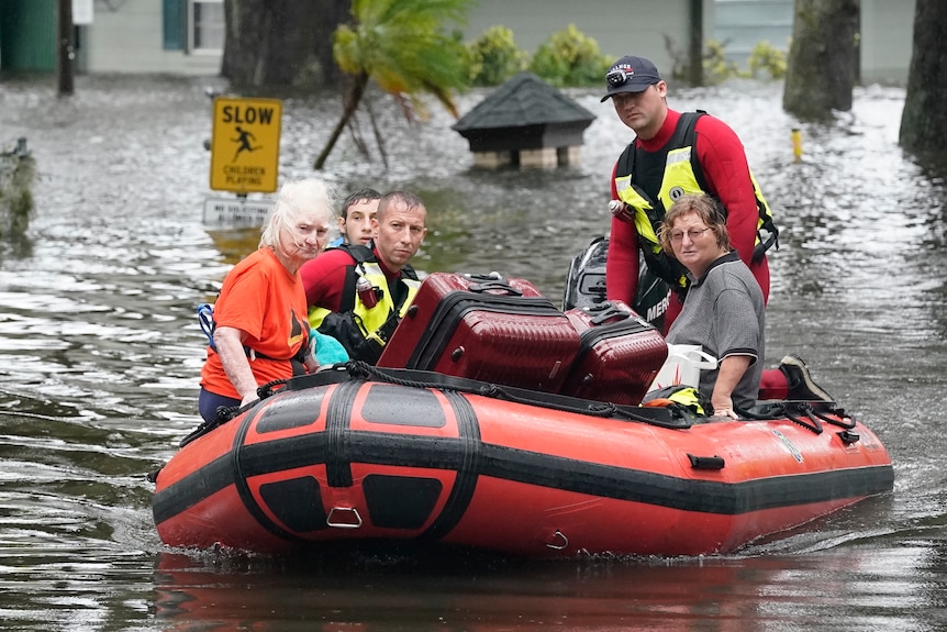 Emergency services rescue stranded residents on boats in flooded waters.