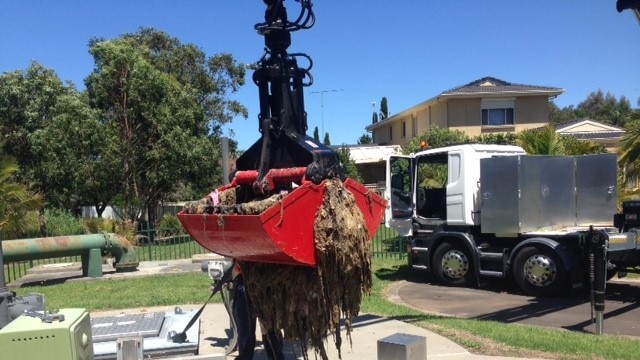 A crane lifting up a huge clump of wet wipes from a sewage pipe.