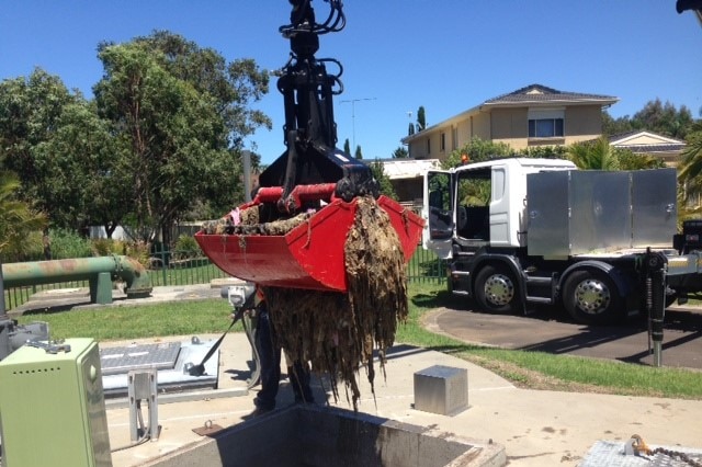 A crane lifting up a huge clump of wet wipes from a sewage pipe.