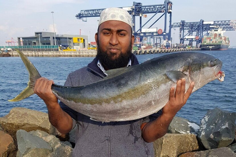 a man holding a large fish at a port
