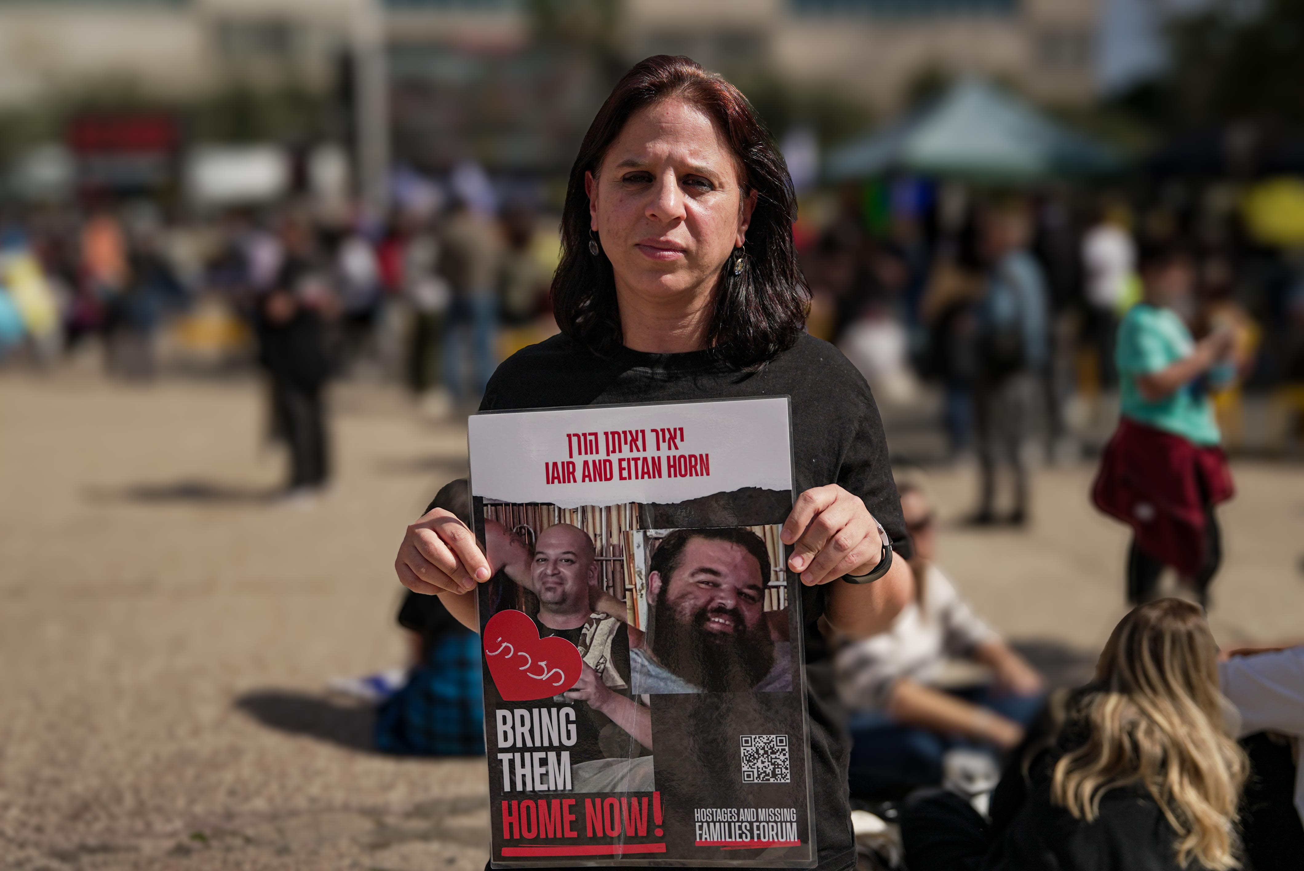A woman holds a sign with the faces of Iair and Eitan Horn, who were taken hostage in Gaza