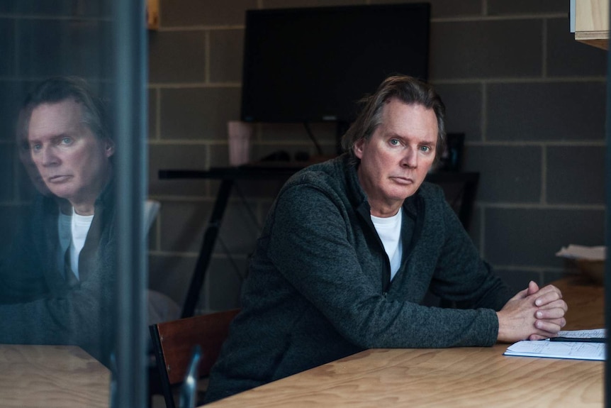 Brett Lockwood sits at a timber table in his architecturally designed home.