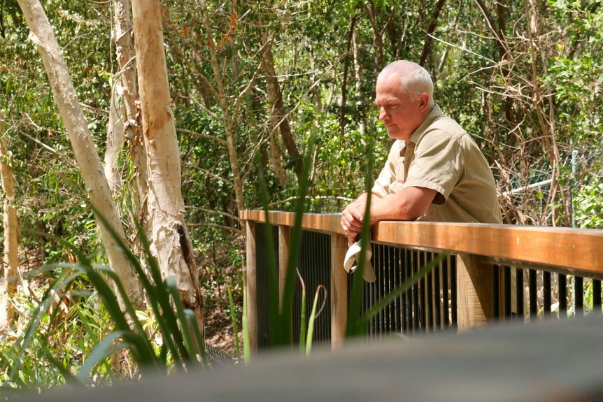 A photo of crocodile handler Drew Melville leaning on a boarwalk at a tourist park.