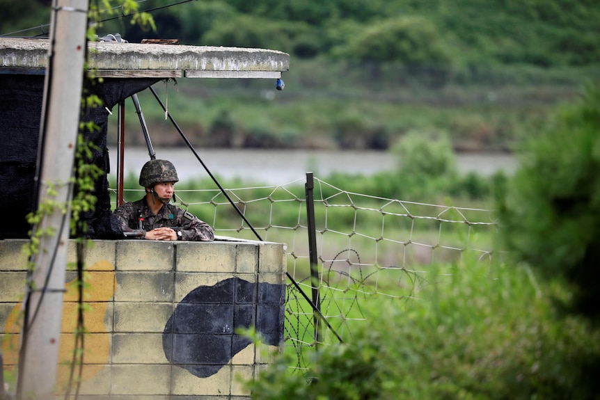 A korean soldier looks out from a concrete viewing post 