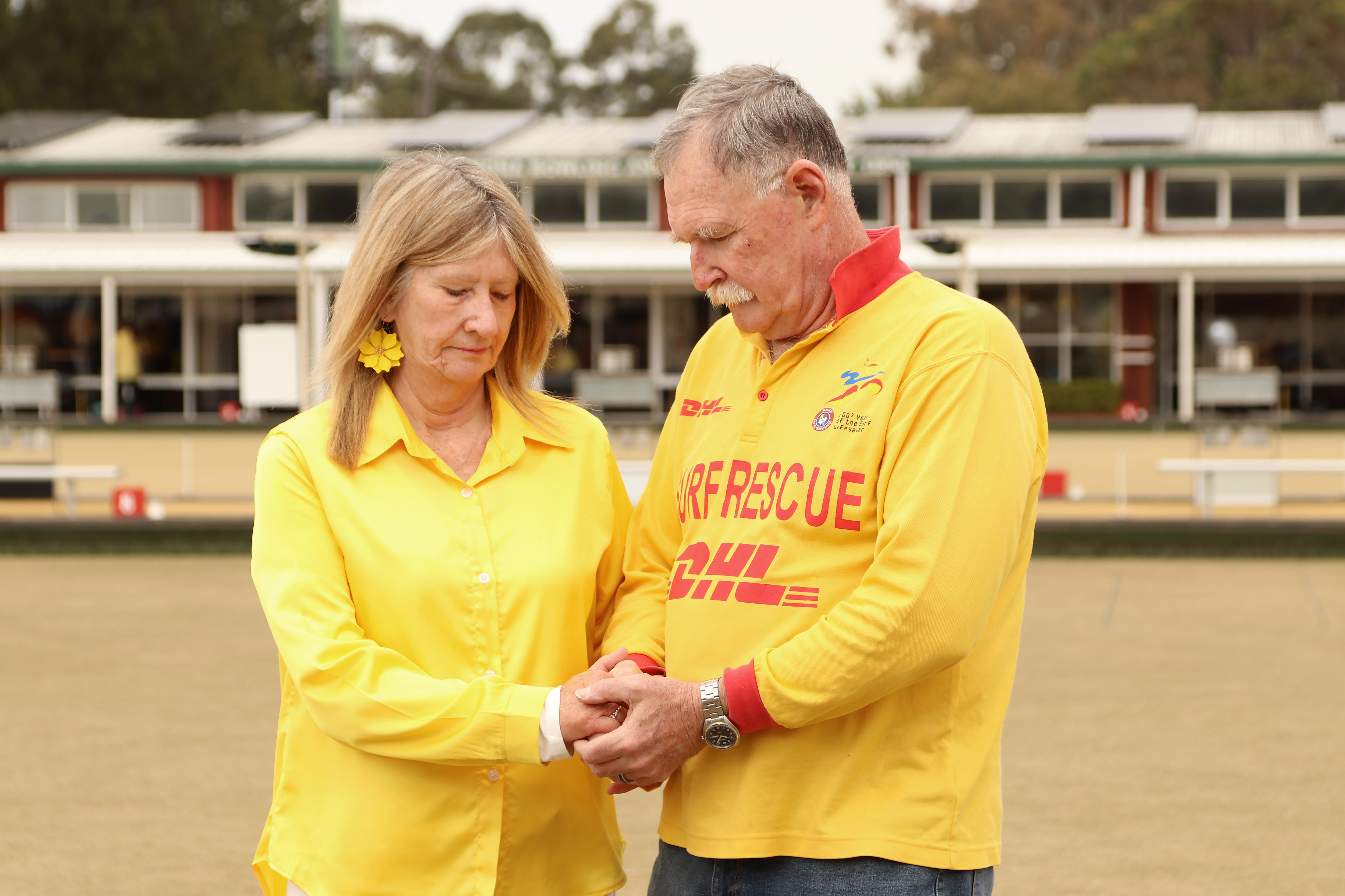 A woman and man holding hands looking down