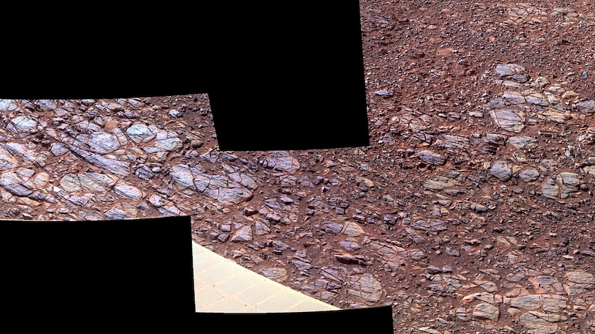 An image shows exposed blue and purple rock among red ground