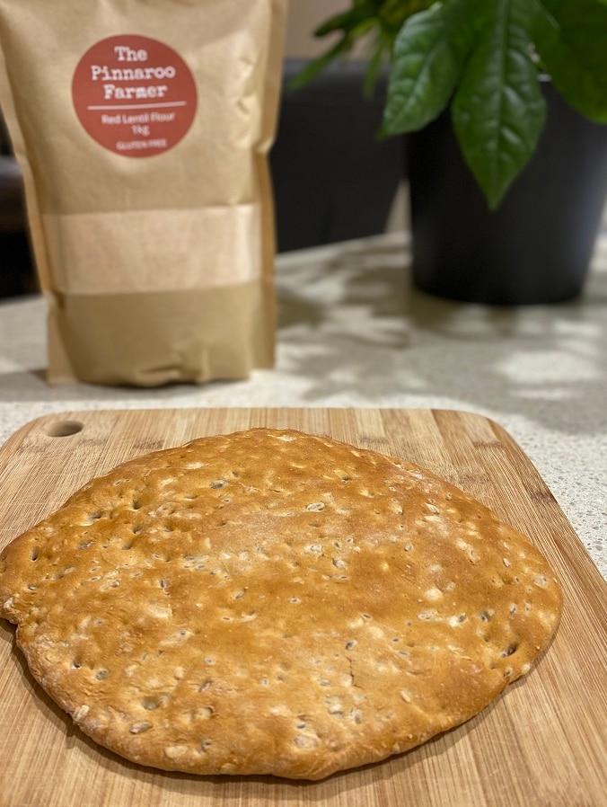 A flat bread and a bag of flour on a a bench.