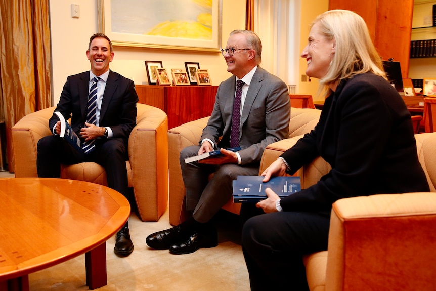 Jim Chalmers, Anthony Albanese and Katy Gallagher laugh while holding budget papers 