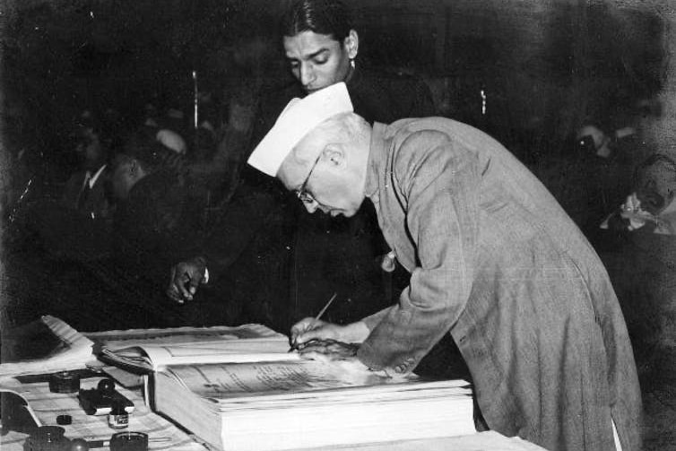 a black and white photo of a man signing a large book