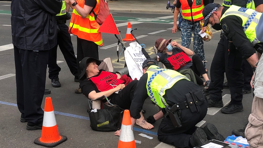 Police kneeling on the ground with a protester on the road